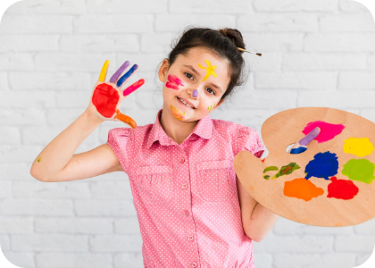 a girl holding an art palette with paint on her face and hands