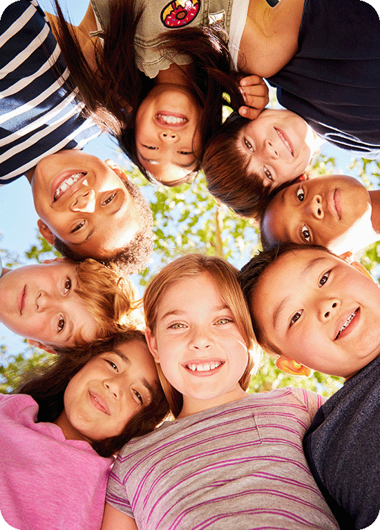 a group of kids gathered in a circle looking down at the ground at the camera